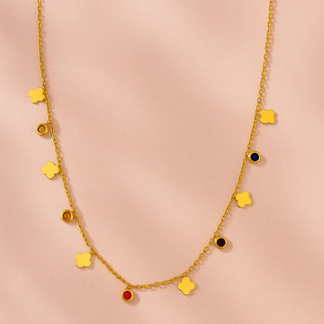 Gold necklace with colorful pendants on a pink background