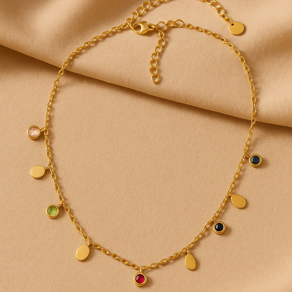 Gold necklace with colorful gemstones on a beige fabric background
