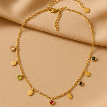 Gold necklace with colorful gemstones on a beige fabric background