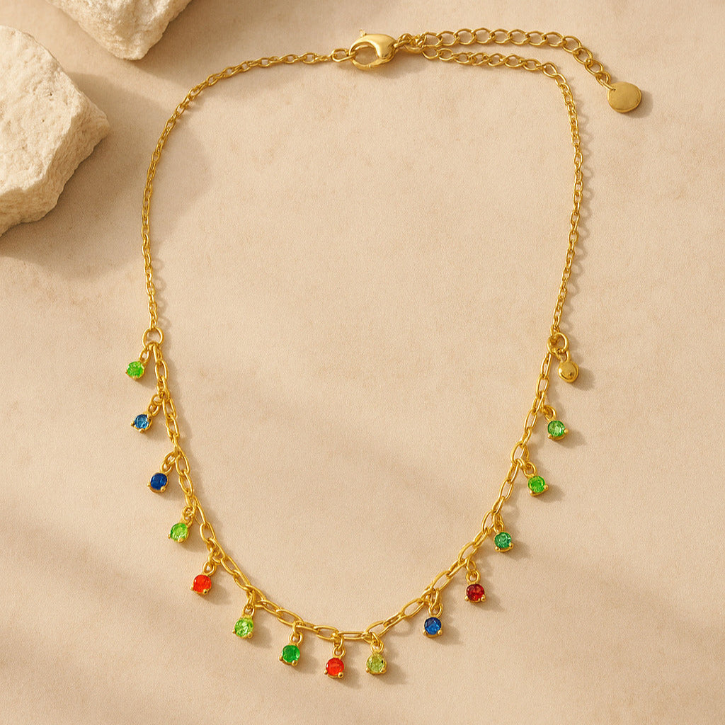 Gold necklace with colorful beads on a beige surface