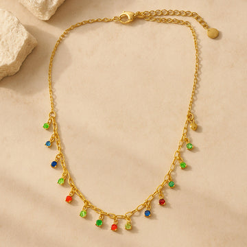 Gold necklace with colorful beads on a beige surface
