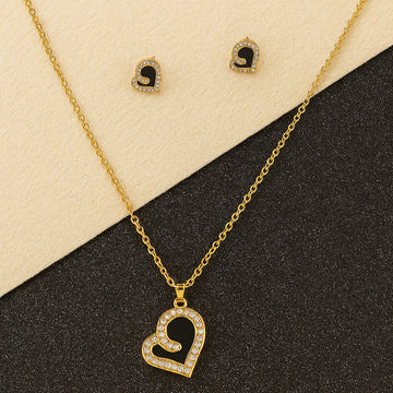 Gold necklace with heart pendant and matching earrings on a black and beige background