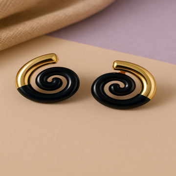 Pair of spiral earrings with gold and black design on a beige surface.