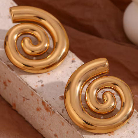 Gold spiral earrings on a textured surface