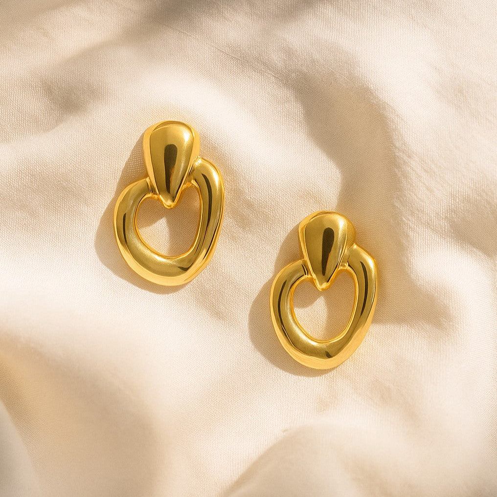 Gold earrings on a beige fabric background