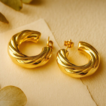Gold hoop earrings on a beige background