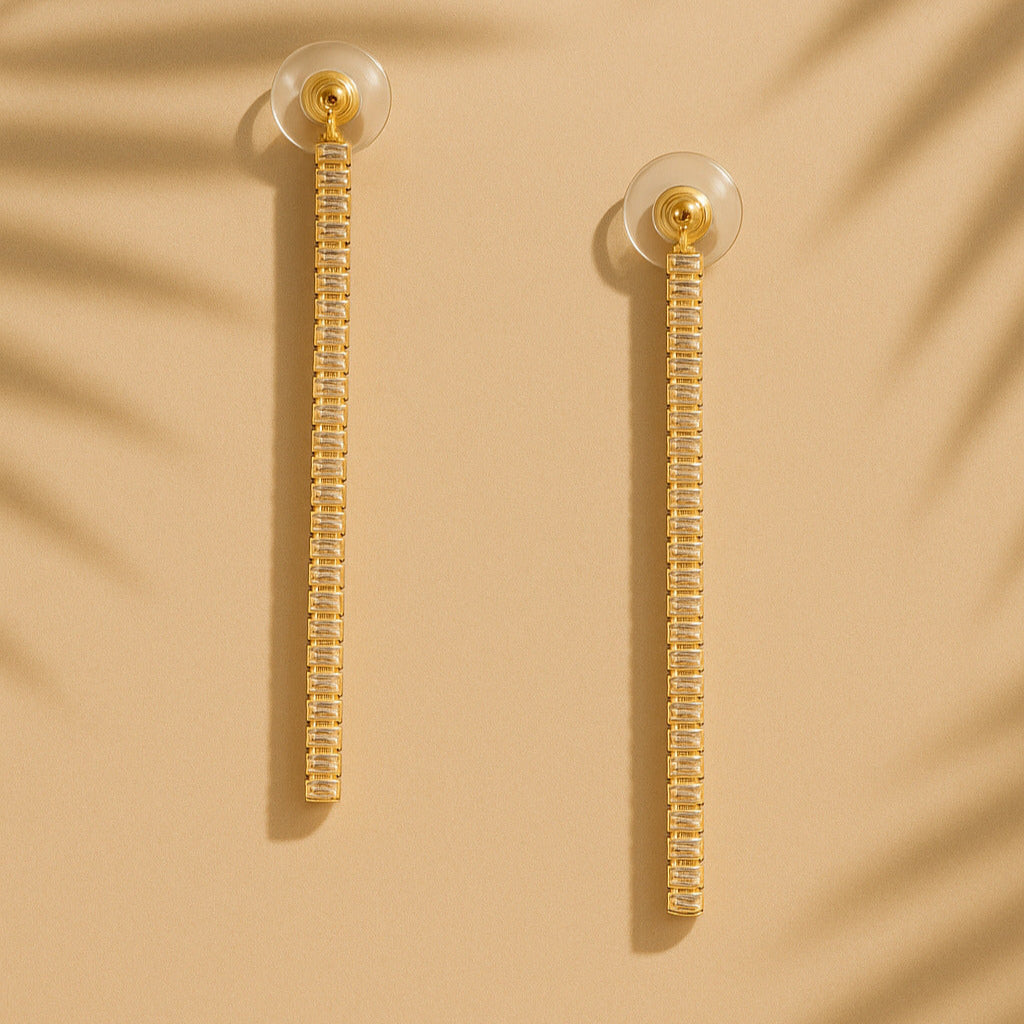 Gold earrings with clear beads on a beige background
