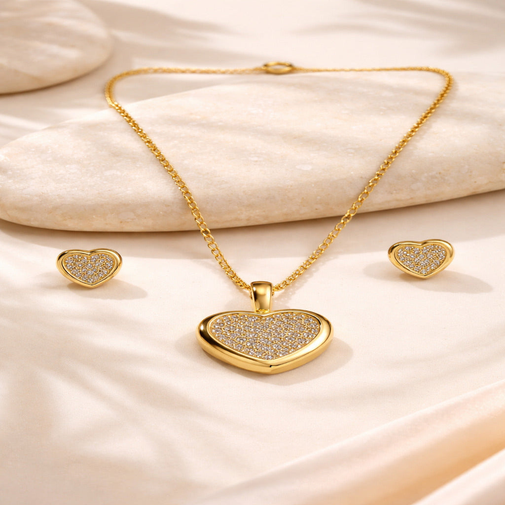 Gold heart-shaped jewelry set on a soft beige fabric background