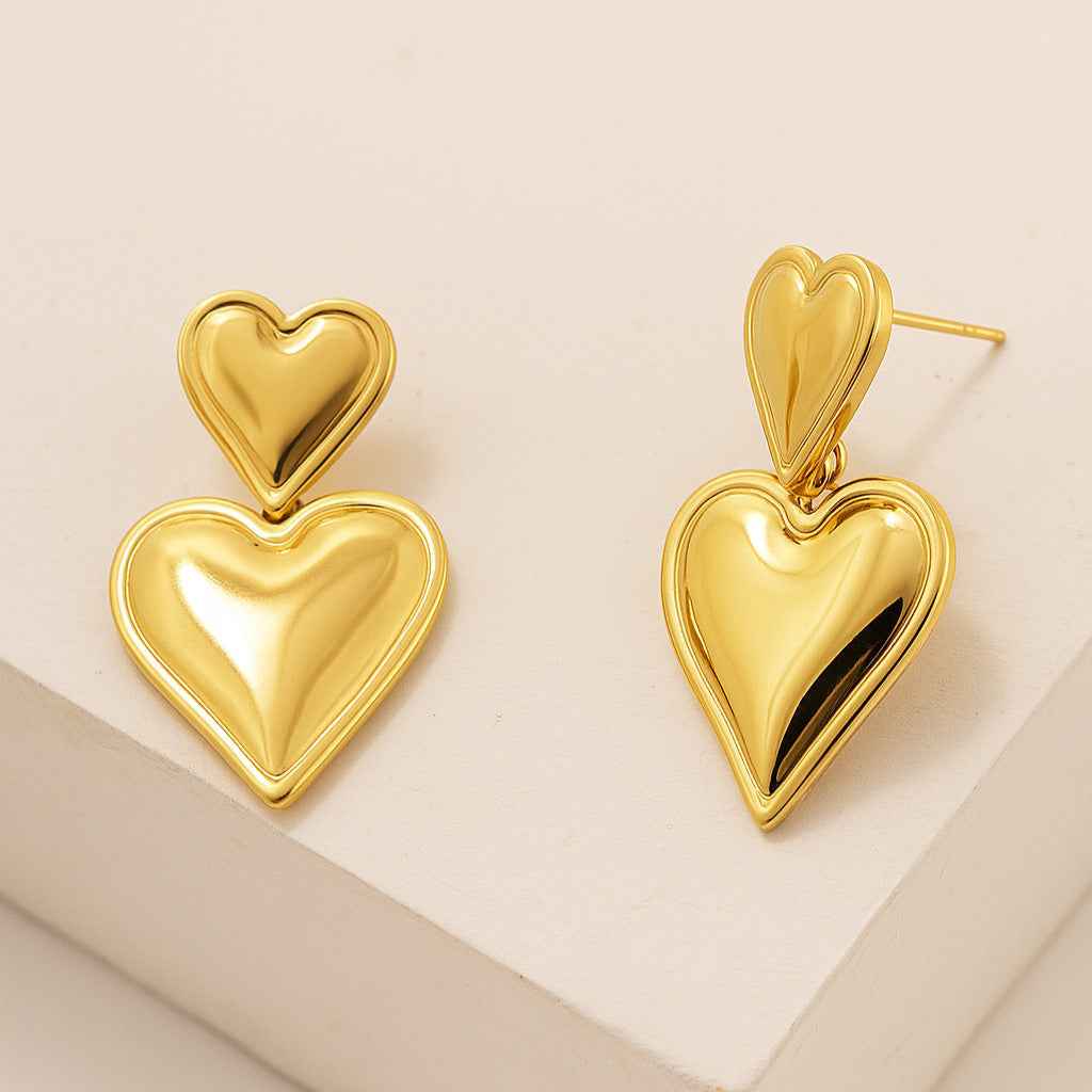 Gold heart-shaped earrings on a beige background
