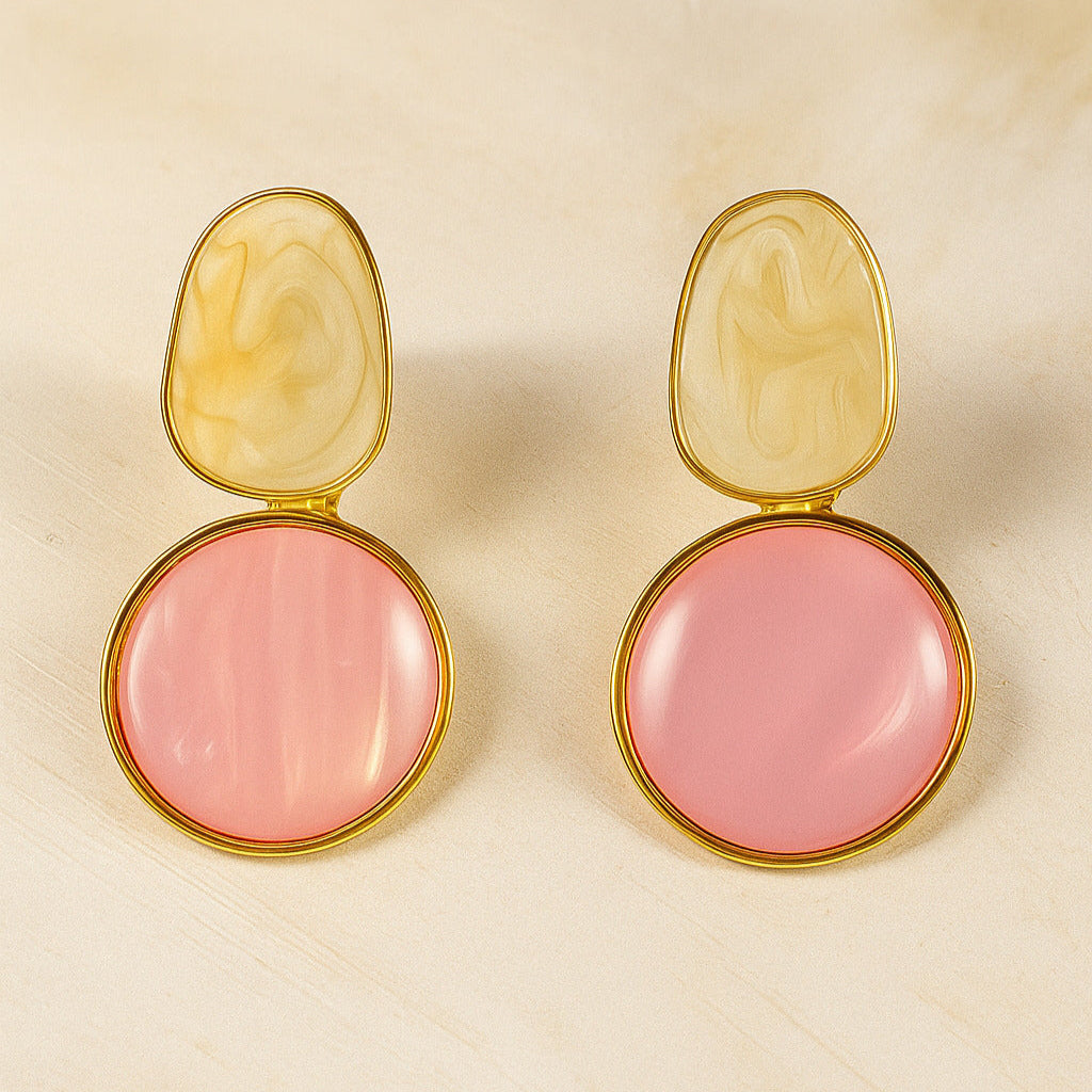 Pair of earrings with pink round stones and gold accents on a beige background