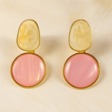 Pair of earrings with pink round stones and gold accents on a beige background