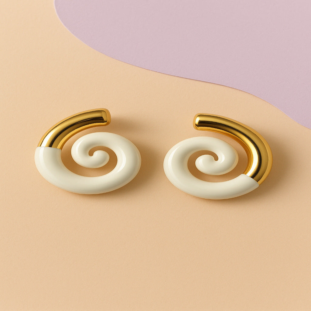 Pair of spiral earrings with gold and white design on a beige background