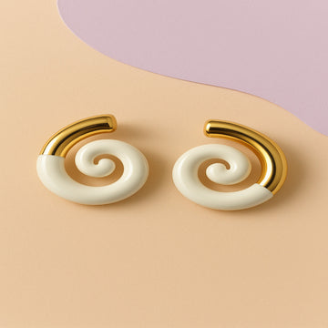 Pair of spiral earrings with gold and white design on a beige background