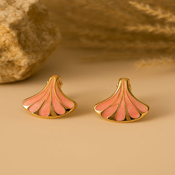 Pair of gold and pink earrings on a beige background