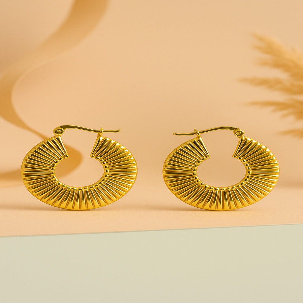 Gold hoop earrings on a two-tone beige and green background