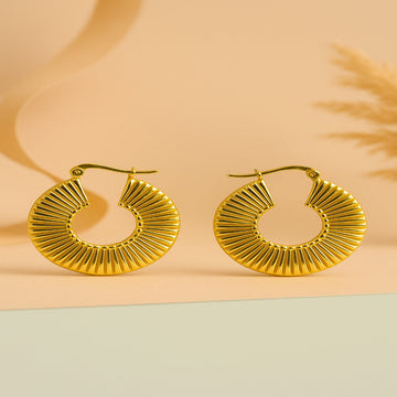 Gold hoop earrings on a two-tone beige and green background
