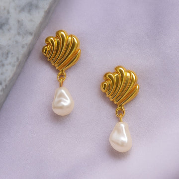 Gold earrings with pearl drops on a light purple fabric background