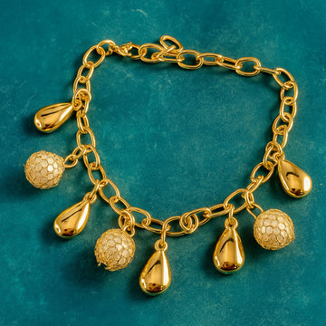 Gold bracelet with various charms on a teal background
