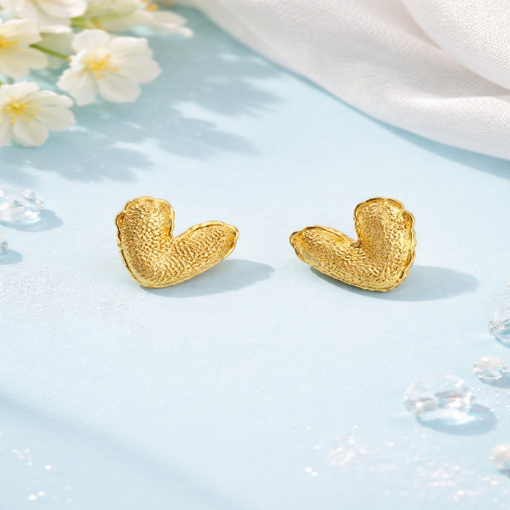Gold earrings on a light blue surface with white flowers
