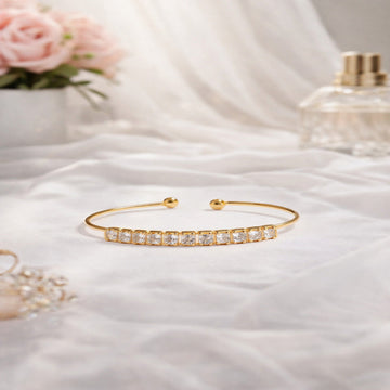 Gold bracelet with clear stones on a soft white fabric background