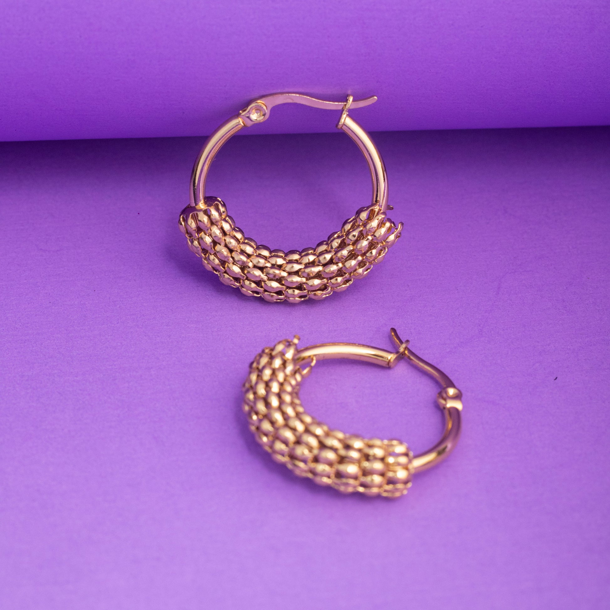 Gold hoop earrings on a purple background