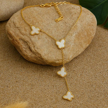 Gold butterfly necklace on a stone surface