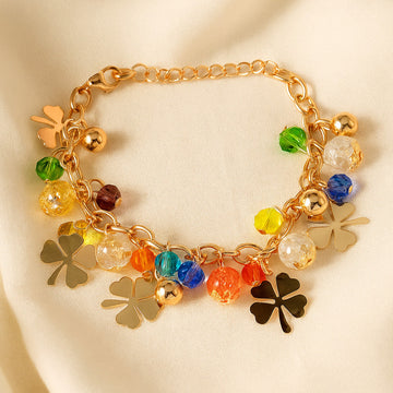 Gold bracelet with colorful charms on a beige background