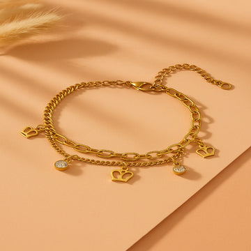 Gold chain bracelet with charms on a peach background