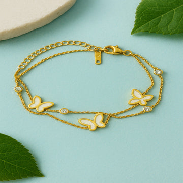 Gold bracelet with butterfly charms on a light blue background