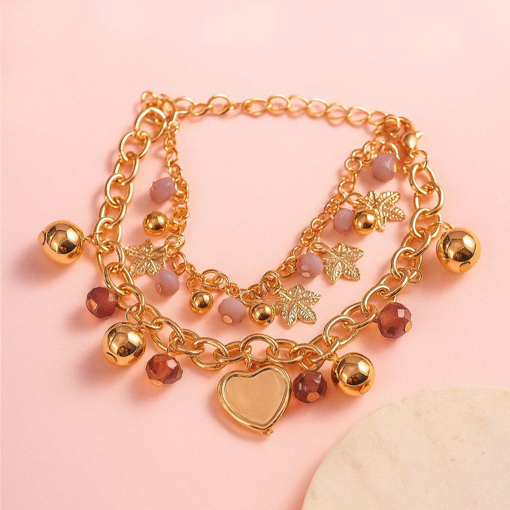 Gold bracelet with heart charm and beads on a pink background