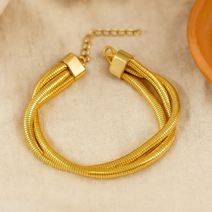 Gold bracelet on a beige fabric background with dried flowers