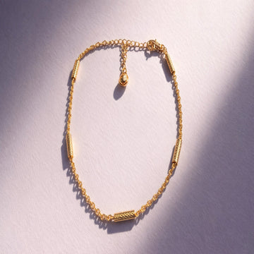 Gold bracelet on a light purple background