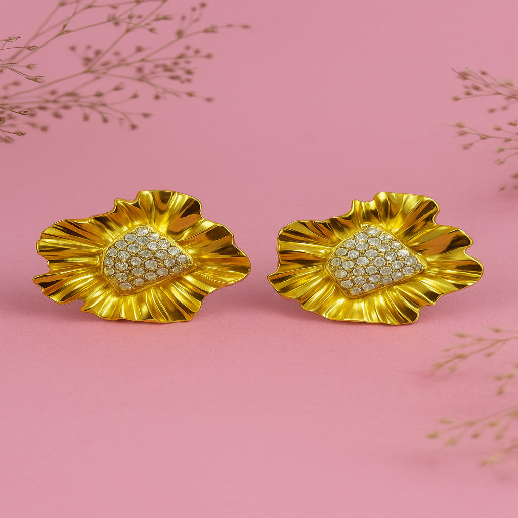 Pair of gold earrings with heart-shaped gemstones on a pink background