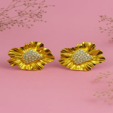 Pair of gold earrings with heart-shaped gemstones on a pink background