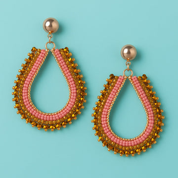 Pair of teardrop-shaped earrings with pink and gold beads on a light blue background