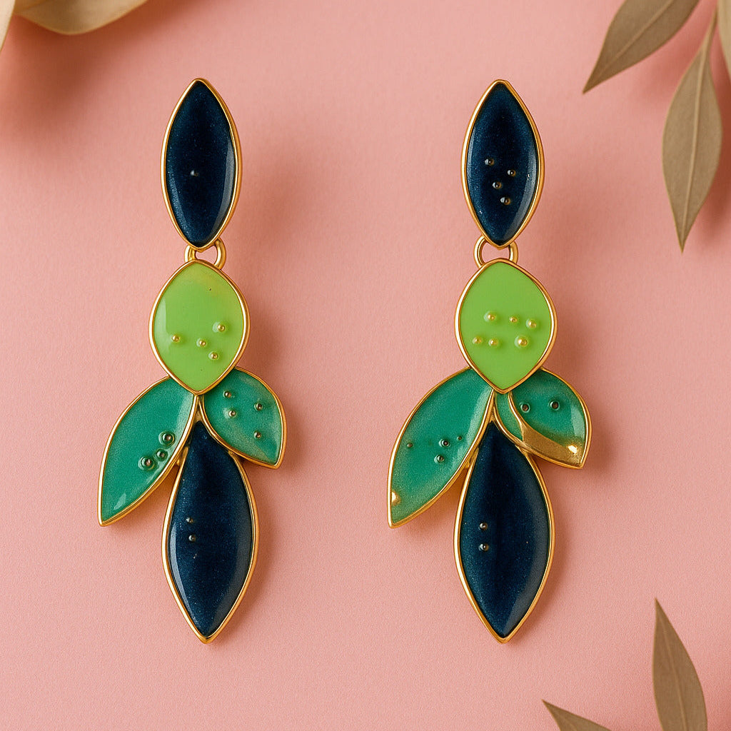 Pair of green and blue leaf-shaped earrings on a pink background