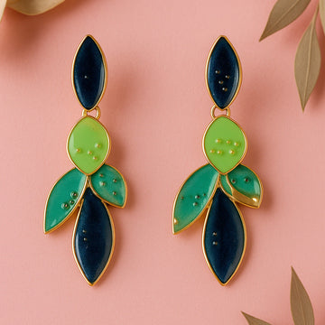 Pair of green and blue leaf-shaped earrings on a pink background