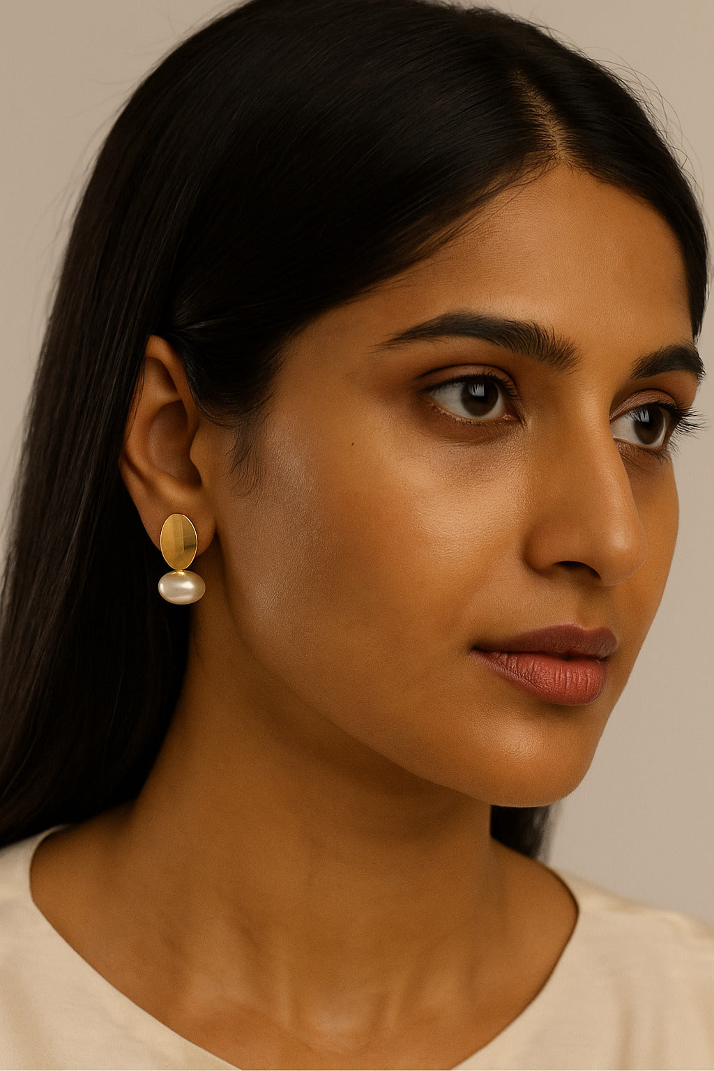 Woman wearing pearl earrings with a neutral background
