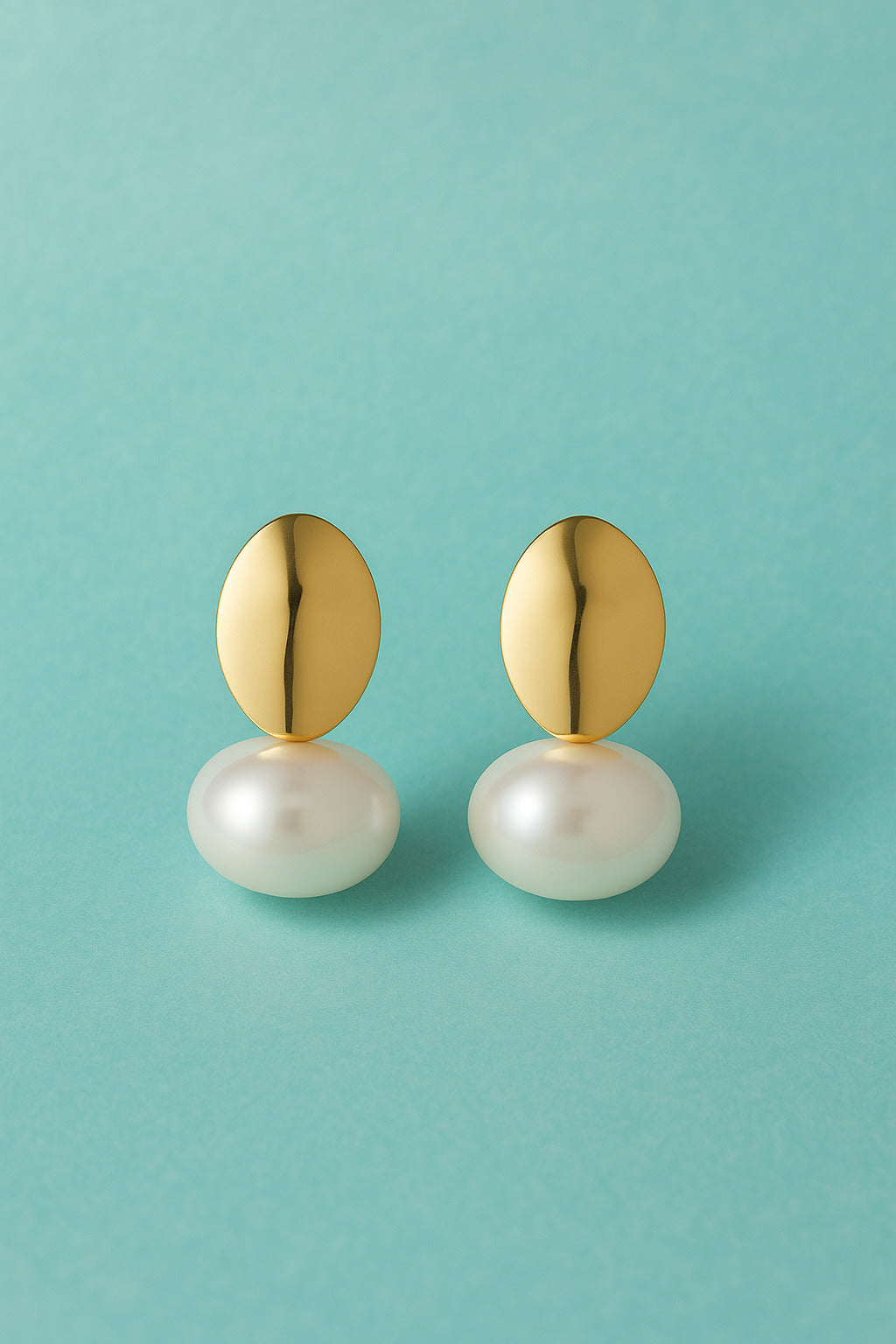 Gold earrings with pearl-like beads on a teal background