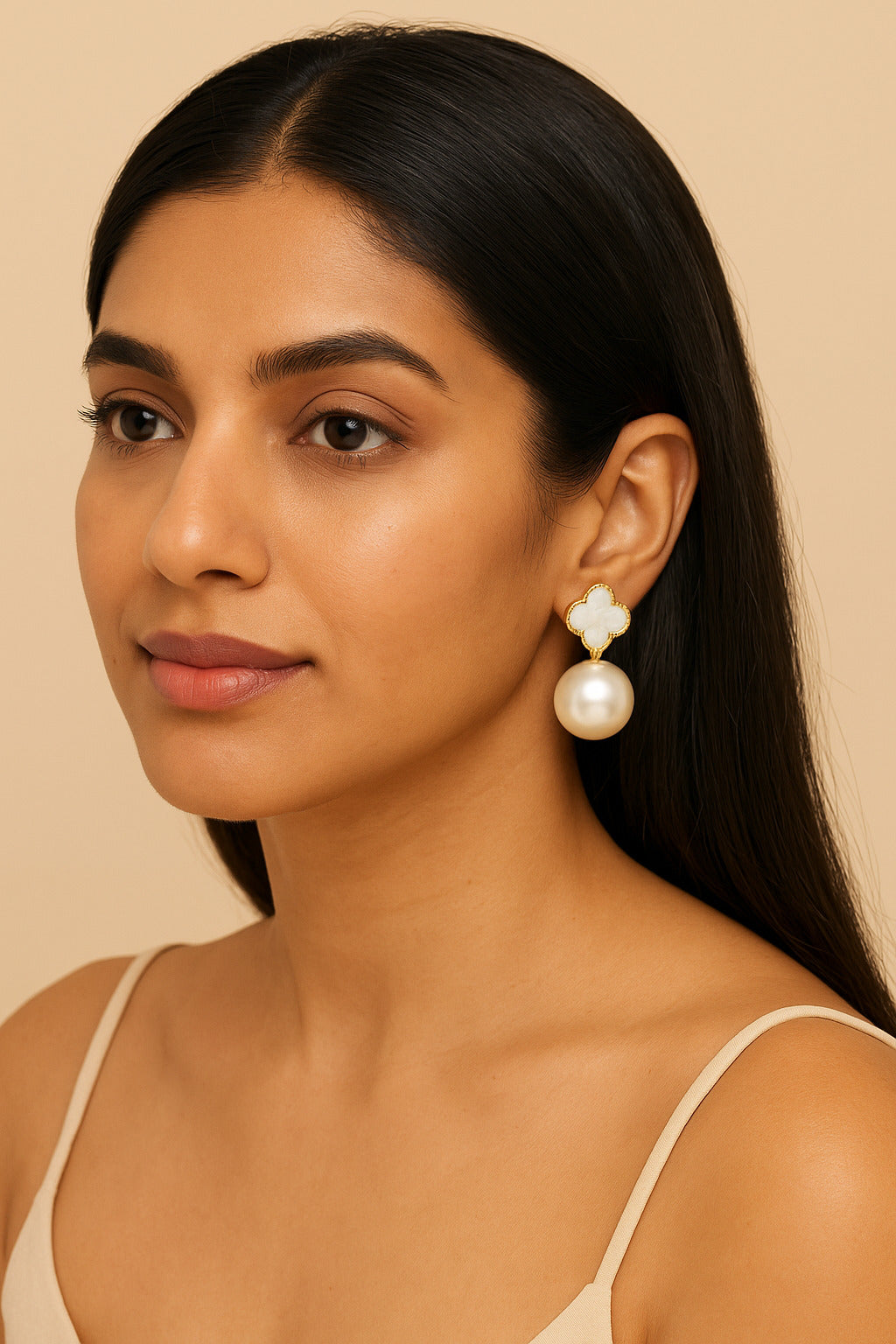 Woman wearing pearl earrings against a beige background