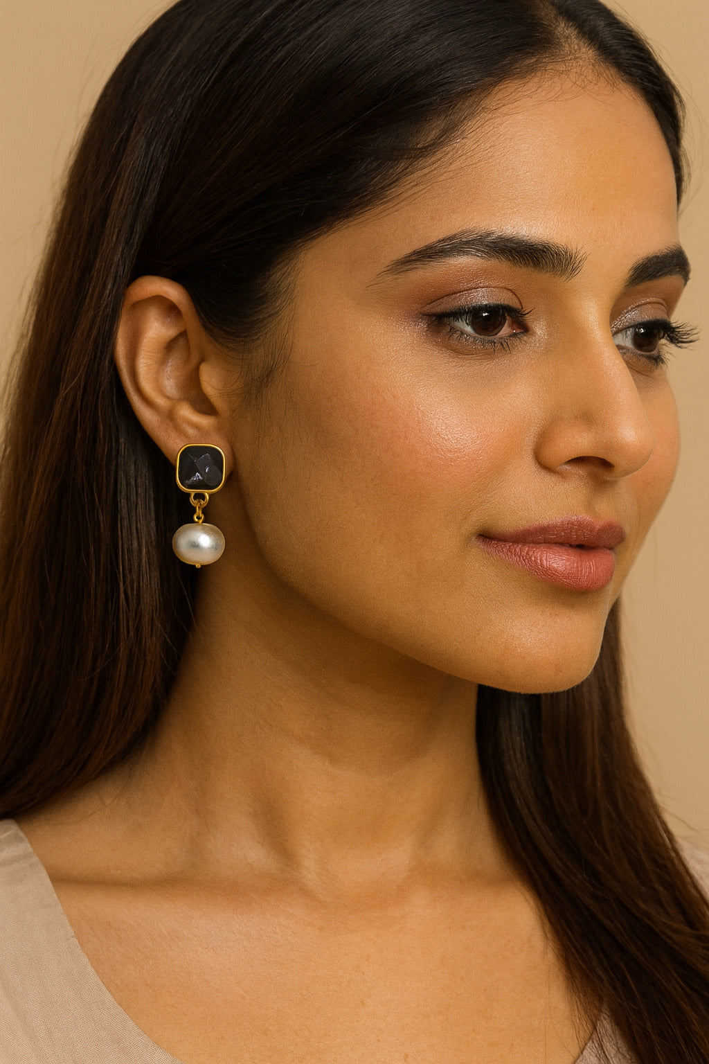 Close-up of a woman wearing a pearl earring with a beige background