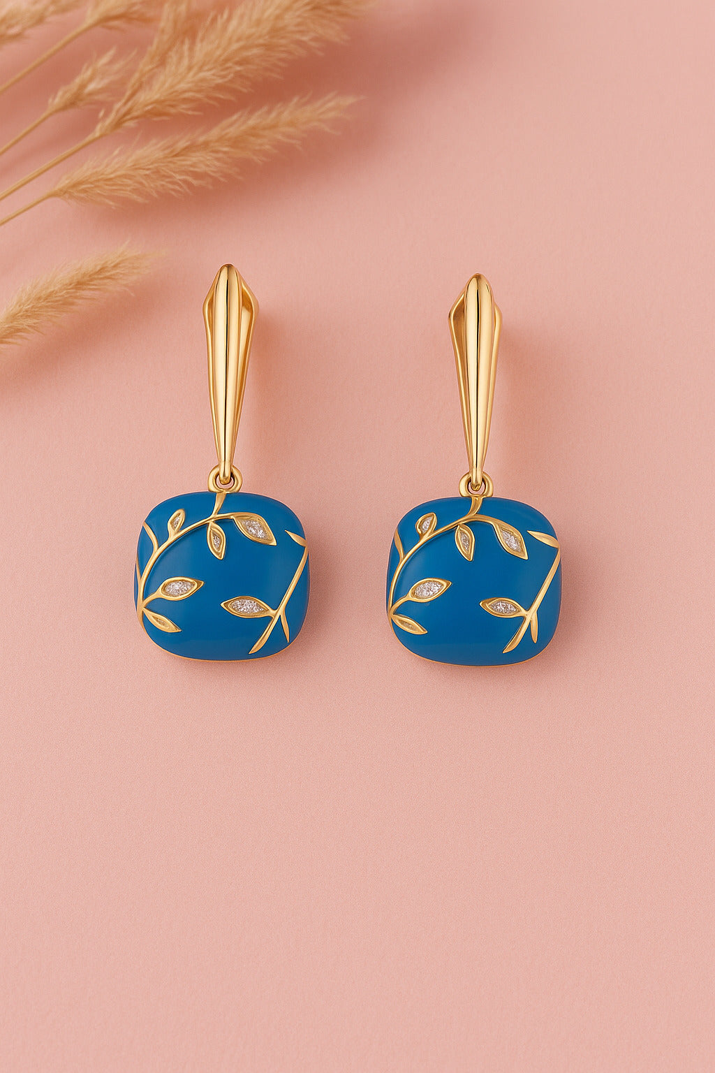 Blue square earrings with gold accents on a pink background