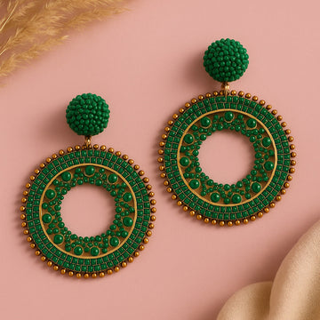 Green and gold earring on a pink background
