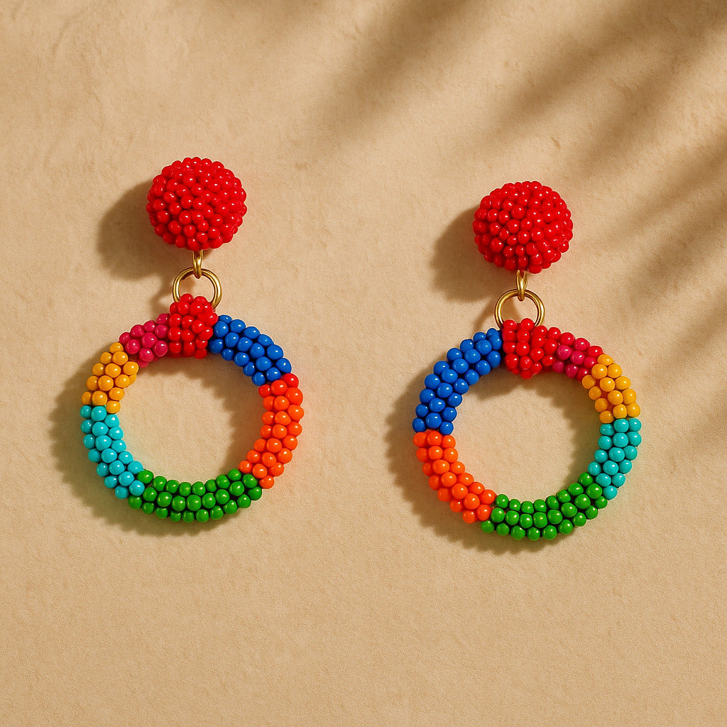 Colorful beaded earrings with red tops on a beige background