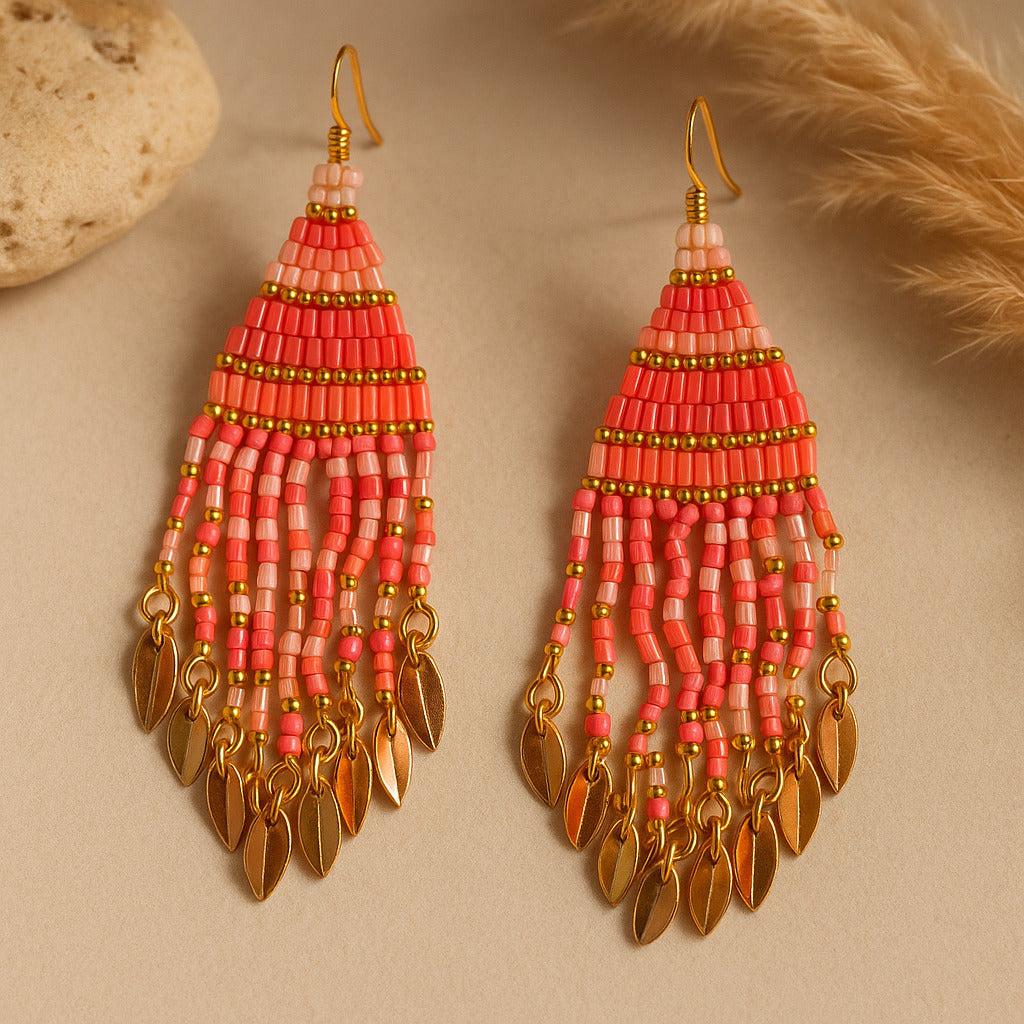 Pair of pink beaded earrings with gold accents on a beige background