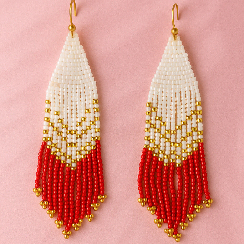 Beaded earrings with white, gold, and red design on a pink background