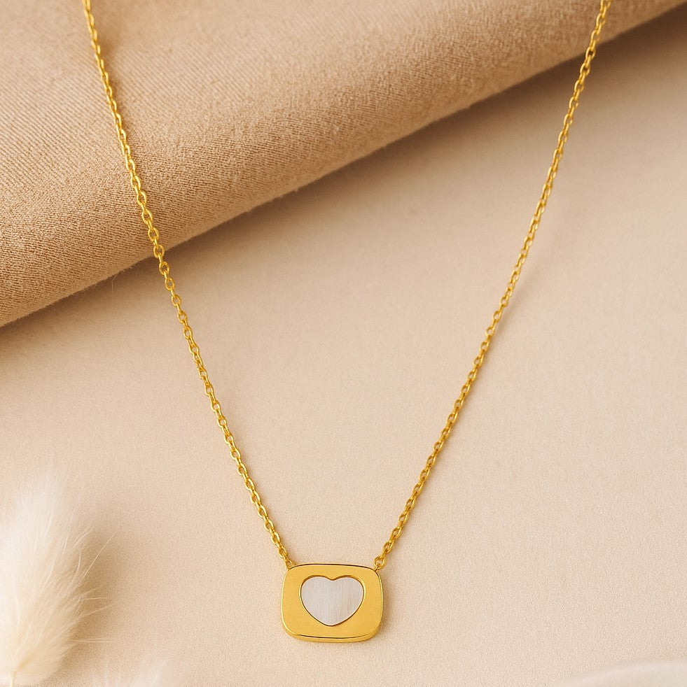 Gold necklace with a heart-shaped pendant on a beige fabric background