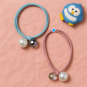 Two hair ties with decorative beads and a penguin-shaped container on a pink background