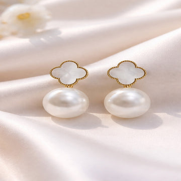 Pearl earrings with gold accents on a soft fabric background