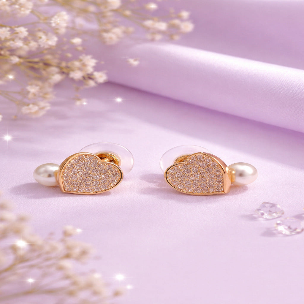 Heart-shaped earrings with glittery center and pearl accents on a soft pink background.